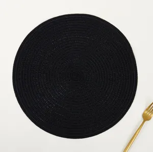 Close-up of black round woven placemat with spiral texture and a golden fork