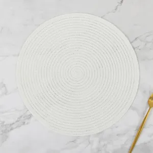 Detail of round white hand-woven ramie placemat with spiral texture on marble background