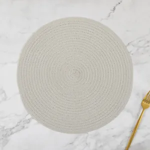 Detail of round woven ramie placemat with spiral texture and gold fork on marble surface