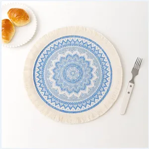 Top-down view of a blue and white mandala coaster with white fringes and cotton texture