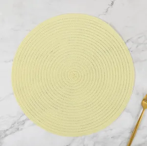 Detail showing handwoven yellow ramie placemat with spiral texture on marble surface