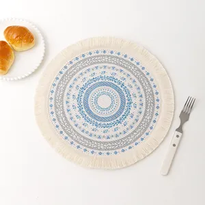 Detail of round mandala placemat with blue tassels and croissant breakfast setting