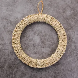Detail of a handmade woven straw wreath with a small hanging loop on a stone surface