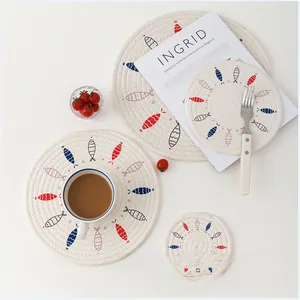 Detail of round woven placemats with colorful fish pattern in a minimalist Nordic setting