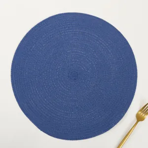 Detail of round blue woven placemat with textured ramie cotton and a gold fork accent