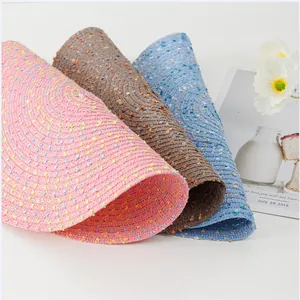 Détail de sets de table ronds tressés en rose, marron et bleu avec taches colorées
