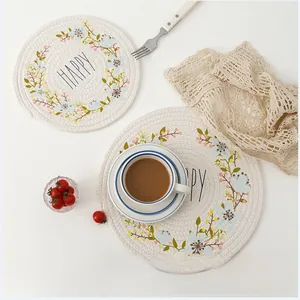 Detail of round woven cotton placemat with floral Happy print and Nordic style