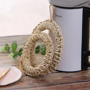 Detail of two handmade woven straw heat resistant mats with hanging loops on wood table