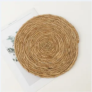 Macro detail of natural straw woven placemat showing tight spiral texture and rustic craft