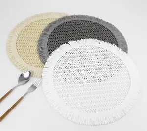 Macro detail of round woven placemats with fringe edge in beige, grey, and white tones