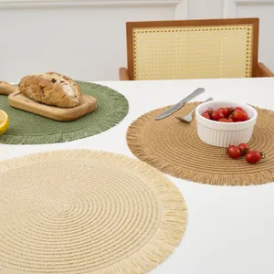 Detailed texture of circular woven placemats with fringe edge in cream and olive