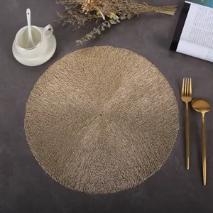Detailed close-up of a round gold PVC placemat with elegant hollow woven feather texture