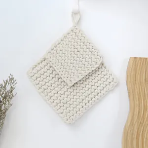 Close-up of thick beige hand-woven cotton cord coasters with texture and hanging loops