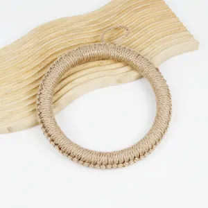 Close-up of handmade round jute placemat with a hanging loop on a wooden tray