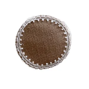 Round jute placemat with white lace fringe and pom-poms on a clean white background