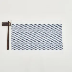 Detail of rectangular woven placemat with blue geometric pattern and white fabric