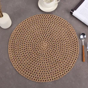 Minimalist round jute woven placemat with hollow mesh texture on a stone table