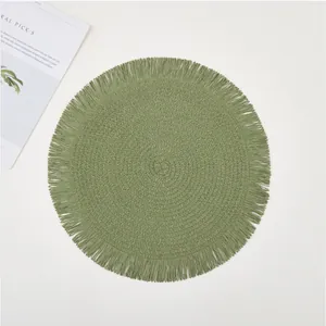 Close-up of grass green woven round placemat showing spiral texture and fringe edge detail