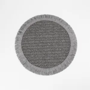 Close-up of a grey round woven placemat featuring intricate textures and fringe edges