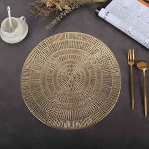 Close-up of a round gold hollow placemat with intricate radial patterns on a dark table