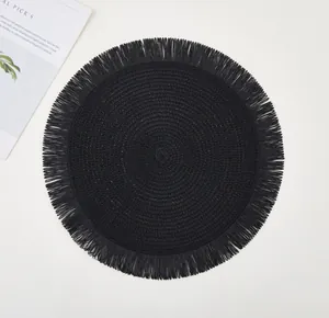 Close-up of black woven round placemat featuring spiral texture and fringe trim