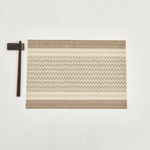 Detail of woven rectangle placemat with beige and brown geometric pattern and chopsticks
