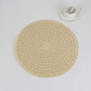 Macro shot of circular beige woven placemat with intricate scalloped crochet texture