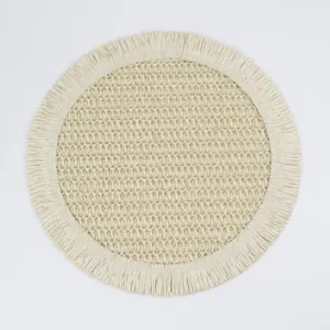 Close-up of bohemian woven coaster featuring fringe edges and cream diamond grid texture