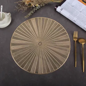Detail of round gold PVC placemat with geometric cutouts on grey stone surface