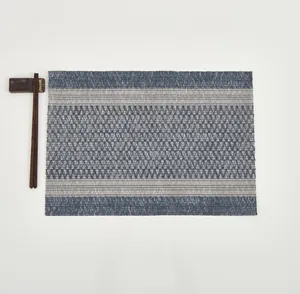 Detailed top view of a woven grey-blue placemat with wooden chopsticks on a white background