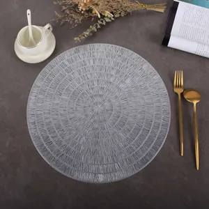 Detailed view of silver PVC round hollow placemat with woven texture on minimalist table