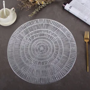 Macro shot of silver hollow PVC round placemat with intricate radial texture on dark table