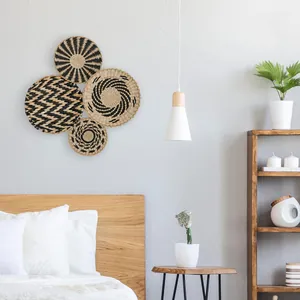 Detail of four handmade seagrass wall baskets in natural and black geometric patterns