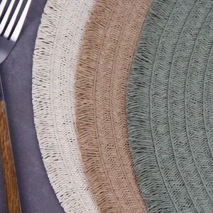 Detail of hand-woven round placemats featuring fringe edges in cream, khaki, and green colors