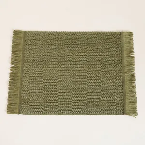 Macro shot of green woven paper placemat showing herringbone texture and fringed edges