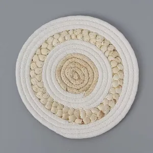 Close-up of a round woven coaster made of natural straw and white cotton rope material