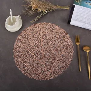 Detail of rose gold hollow PVC round placemat with elegant coral leaf texture on marble
