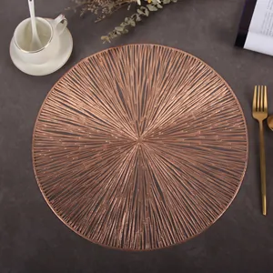 Detail of round rose gold cutout placemat with radial lines on dark textured surface