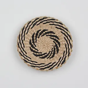 Detailed view of woven seagrass wall decor featuring a black spiral pattern on light grey background