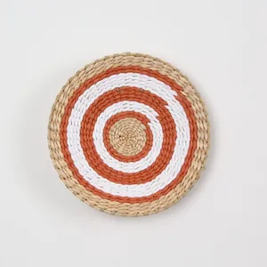 Detailed close-up of a bohemian woven seagrass wall plate with concentric orange patterns