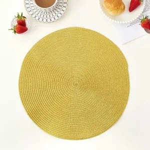 Close-up of a yellow woven round placemat with spiral texture on a dining table