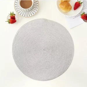 Detail of round woven heat-resistant placemat in light grey for stylish table setting