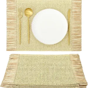 Bohemian rectangle woven place mat with fringes and golden cutlery on white background