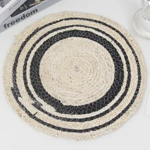 Handwoven natural round straw placemat with black concentric circle design and thermal insulation