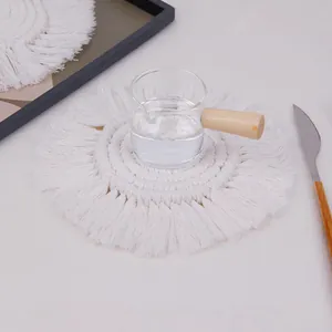Close-up of white woven cotton coaster with tassels under a glass cup in a Nordic setting