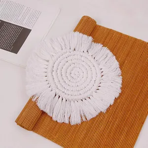Detailed macro of white Macrame round cotton coaster with fringe on a wooden desk