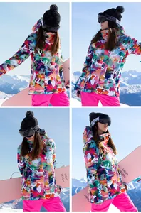 Women's colorful camo ski jacket and pink pants set shown in outdoor snow mountain scenery