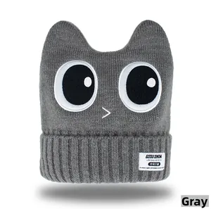 Detail of grey knitted ski hat with cartoon eyes and ribbed cuff texture