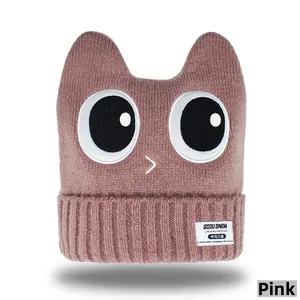 Detail of dusty pink knitted cat-ear beanie showing textured warm wool fabric and label