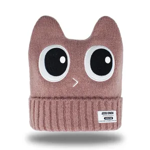 Knitted ski hat with cartoon eyes and ear flaps in dusty rose for winter warmth